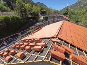 Pose de tuiles en terre cuite sur liteaux et membrane BMI Monier lors d'une rénovation de toiture en montagne.
